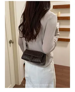 Vista posteriore di una mini borsa a tracolla intrecciata marrone scuro su modella.