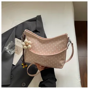 Close-up detail of a stylish pink polka dot shoulder bag featuring a cute flower charm