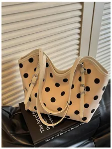 Elegante bolso tote de lona con lunares sobre libros con fondo blanco de persianas