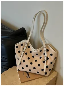Bolso tote retro de lona con lunares negros presentado sobre un pedestal de piedra