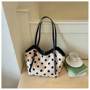 Primer plano de bolso tote de lona con lunares retro y correas de cuero negras