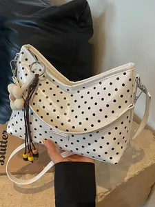 White polka dot bucket bag with elegant flower charm and adjustable shoulder strap