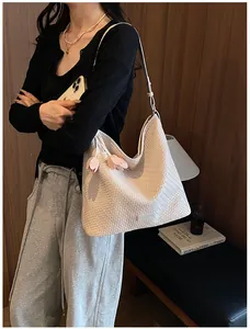 Close-up of a large cream woven shoulder bag with pink floral decoration worn by a model