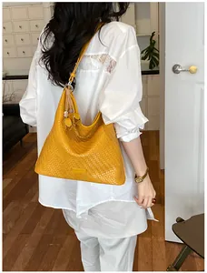 Detailed view of yellow woven tote bag worn by model in white casual outfit