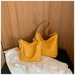 Two yellow woven hobo bags displayed on white cloth with a wood background