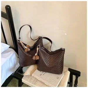 Detailed view of two dark brown woven tote bags on a rustic chair in a bedroom