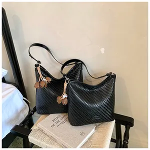 High-quality detail of two black woven shoulder bags featuring elegant floral tassel charms