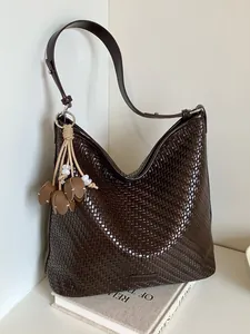 Large dark brown woven tote bag for women featuring a floral charm and wide shoulder strap