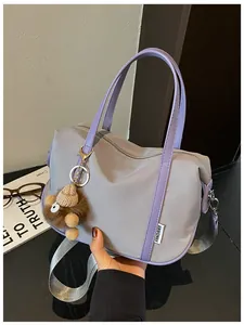 Détail d'un sac cabas en nylon violet clair avec un porte-clés en peluche marron
