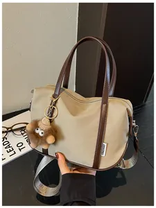 Gros plan sur un sac cabas en nylon kaki avec breloque peluche et anses en cuir