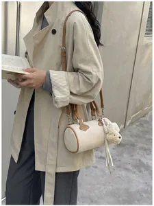 Close-up of canvas barrel bag with lamb charm on model wearing beige trench coat