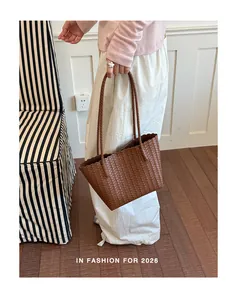 Macro view of a classic brown woven tote bag held by a model in a stylish indoor setting