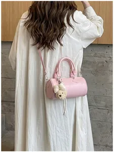 Elegant pink cylinder crossbody bag for women featuring a cute plush bear charm decoration