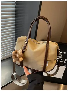 Gros plan d'un sac cabas en nylon kaki élégant avec des anses brunes et un petit porte-clé.