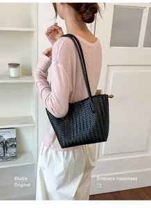 Elegant black woven leather tote bag shown on a model in a minimalist studio interior