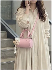 Elegant pink mini cylinder crossbody bag for women featuring a cute teddy bear charm accessory