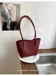 Detail of a burgundy woven tote bag with slim handles in a vintage chic style.