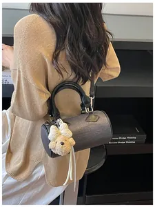 Detailed view of grey textured barrel bag with cute plush bear keychain accessory