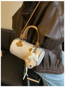 Detailed view of an elegant woven barrel handbag featuring a cute plush bear charm