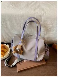 Gros plan d'un sac cabas en nylon gris-violet avec un adorable charm monstre en peluche