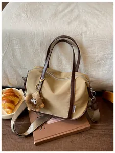 Sac cabas élégant en nylon kaki avec breloque lion en peluche et bandoulière amovible.