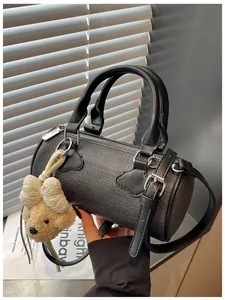 Close-up detail of stylish black textured barrel handbag featuring a cute bear charm