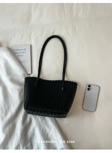 Stylish black woven shoulder tote bag with large capacity, shown in a lifestyle flat lay