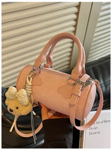 Detailed view of an elegant pink tweed barrel bag featuring a cute bear plush charm