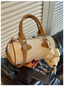 Macro view of a woven cream barrel handbag featuring brown leather trim and a cute bear charm