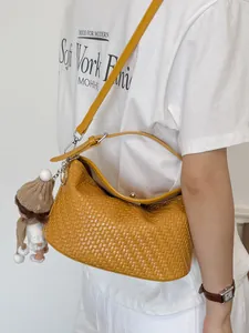 Κομψή κίτρινη πλεκτή τσάντα χιαστί bucket bag με ένα χαριτωμένο μενταγιόν κούκλας