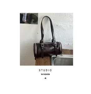Detail view of a vintage dark brown cylinder pillow bag on a rustic wooden ledge
