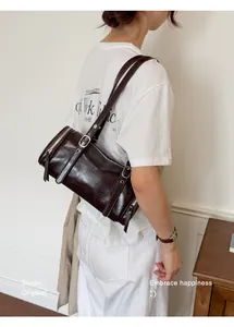 Detail of a retro brown leather pillow bag worn by a model in a minimalist setting