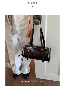 Vintage-style glossy dark brown leather barrel bag shown as a chic underarm shoulder bag.
