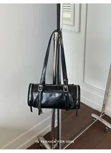 Detailed close-up of a vintage black glossy leather pillow shoulder bag hanging on a rack