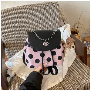 Detailansicht eines rosa-schwarzen gepunkteten Rucksacks mit Plüschbären auf weißem Tuch