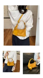 Yellow woven hobo bag with adjustable strap and decorative charm shown in lifestyle detail