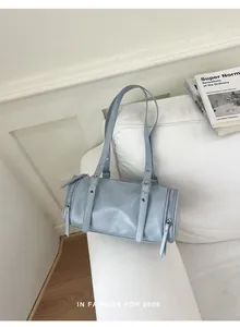 Light blue vintage minimalist pillow bag displayed on a white sofa in a lifestyle setting