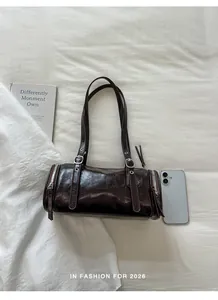 Vintage dark brown barrel pillow bag shown with a smartphone for scale reference