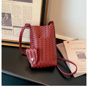 Détail d'un sac à bandoulière tressé rouge pour téléphone avec des livres vintage.