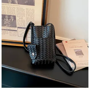Vue détaillée de la texture tissée d'un mini sac à bandoulière noir pour téléphone