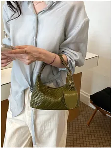 Detailed view of an olive green woven dumpling handbag with a small charm pouch