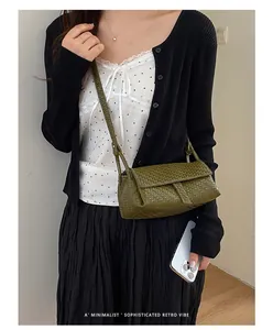 Un primo piano di una mini borsa a tracolla intrecciata verde per cellulare retrò.