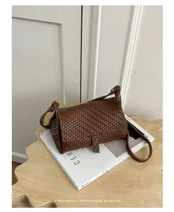Vista dettagliata della mini borsa a tracolla intrecciata marrone su una rivista.