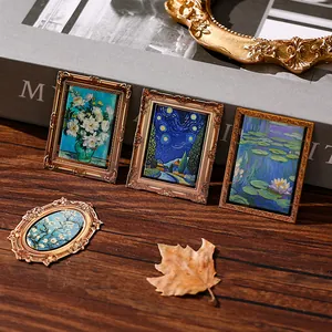 Vintage miniature oil painting metal bookmarks with ornate gold frames on a wooden desk.