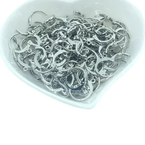 Ganchos de pendientes plateados en un plato de cerámica blanca con forma de corazón.
