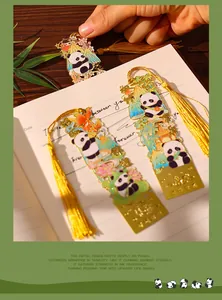 Close-up view of exquisite metal panda bookmarks with elegant yellow tassels on a notebook.
