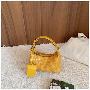 Close-up detail of a yellow woven handbag featuring a sturdy top handle and metal zipper