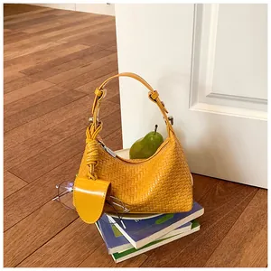 Detailed view of a yellow woven handbag with knotted handle and matching mini pouch