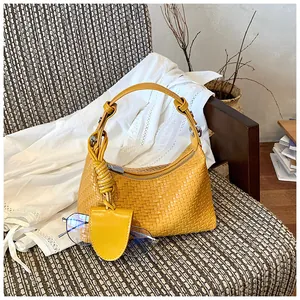 Yellow woven dumpling handbag with mini charm for elegant commuter style