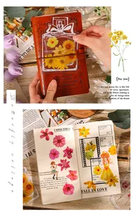 Artistic close-up of vintage floral stickers and clear bottle bookmarks on a diary.